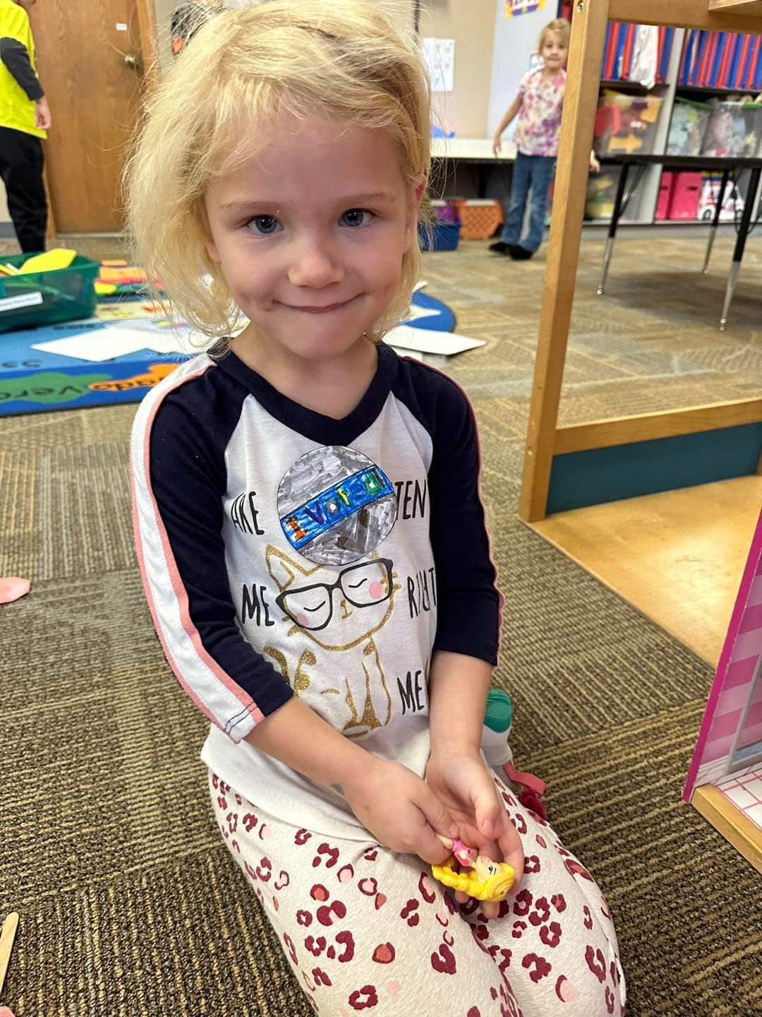A little girl is sitting on the floor holding a toy car.