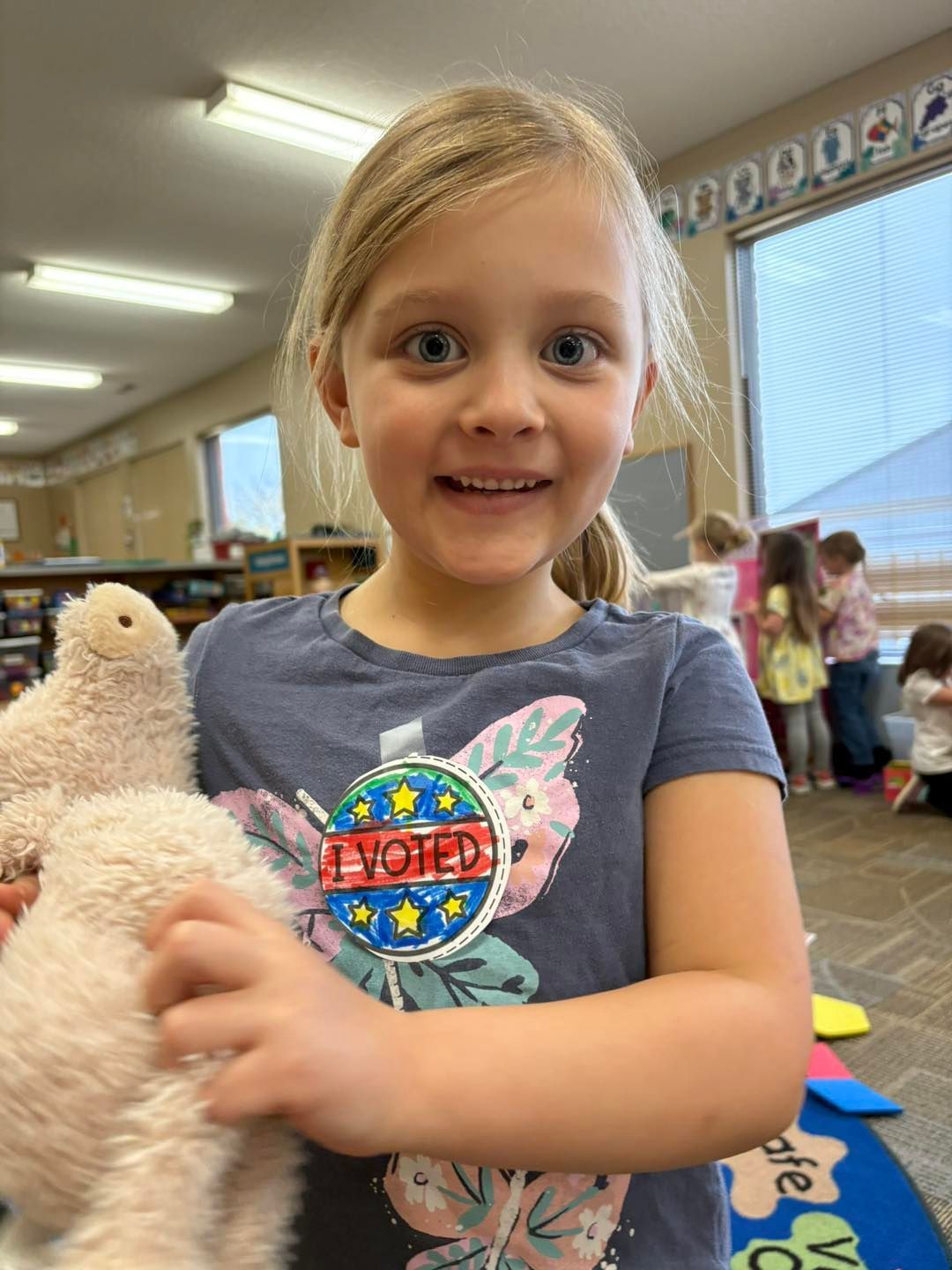 A young girl is holding a stuffed animal in a classroom.