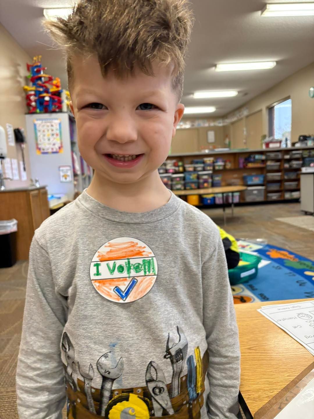 A young boy is wearing a i voted sticker on his shirt.