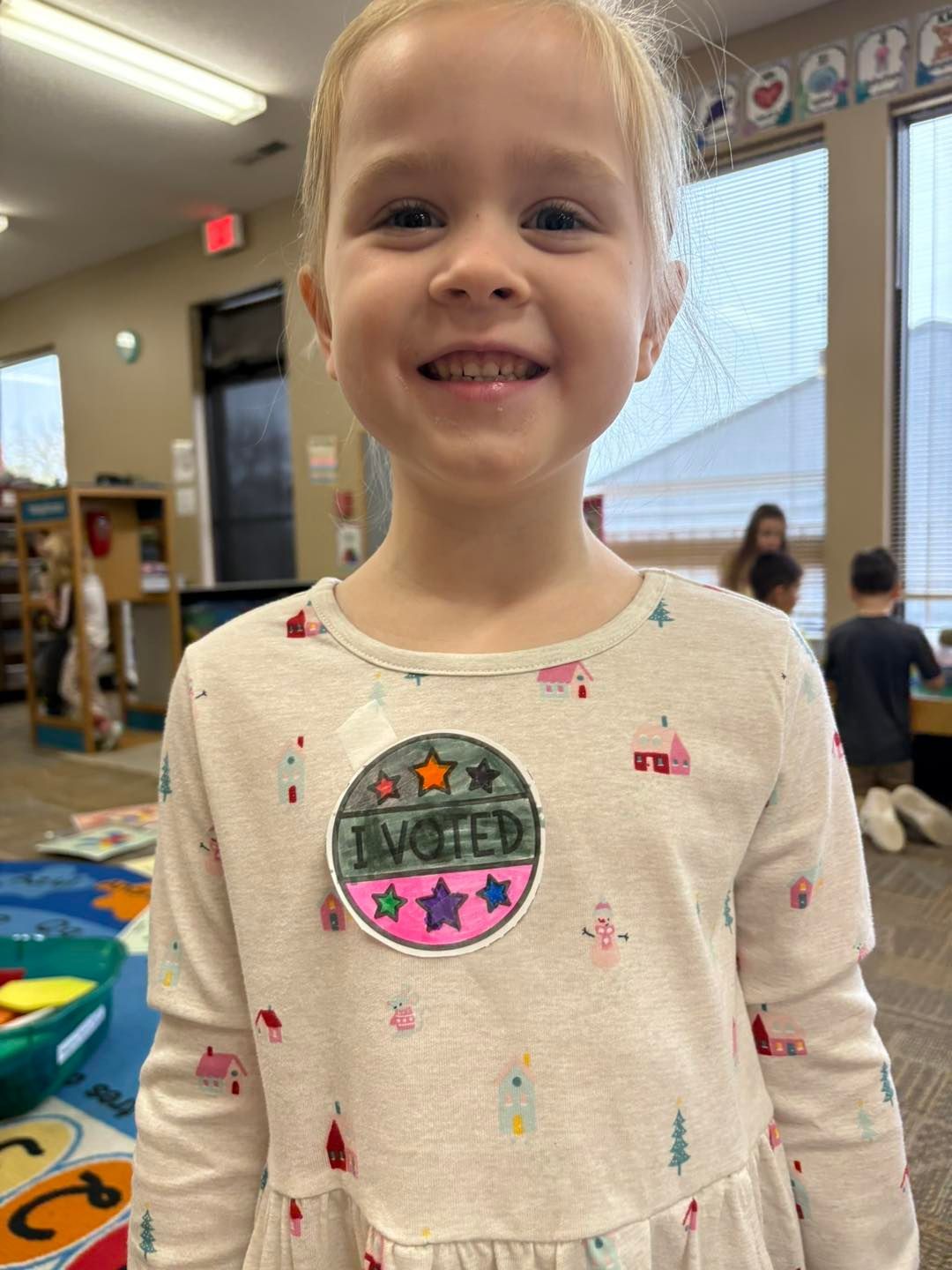 A little girl wearing a sweatshirt is smiling for the camera.