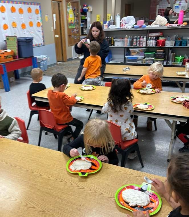 A group of children are sitting at tables eating food.