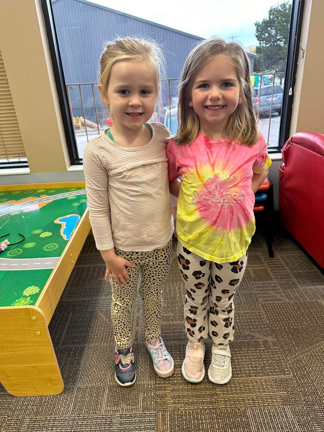 Two little girls are standing next to each other in a room.