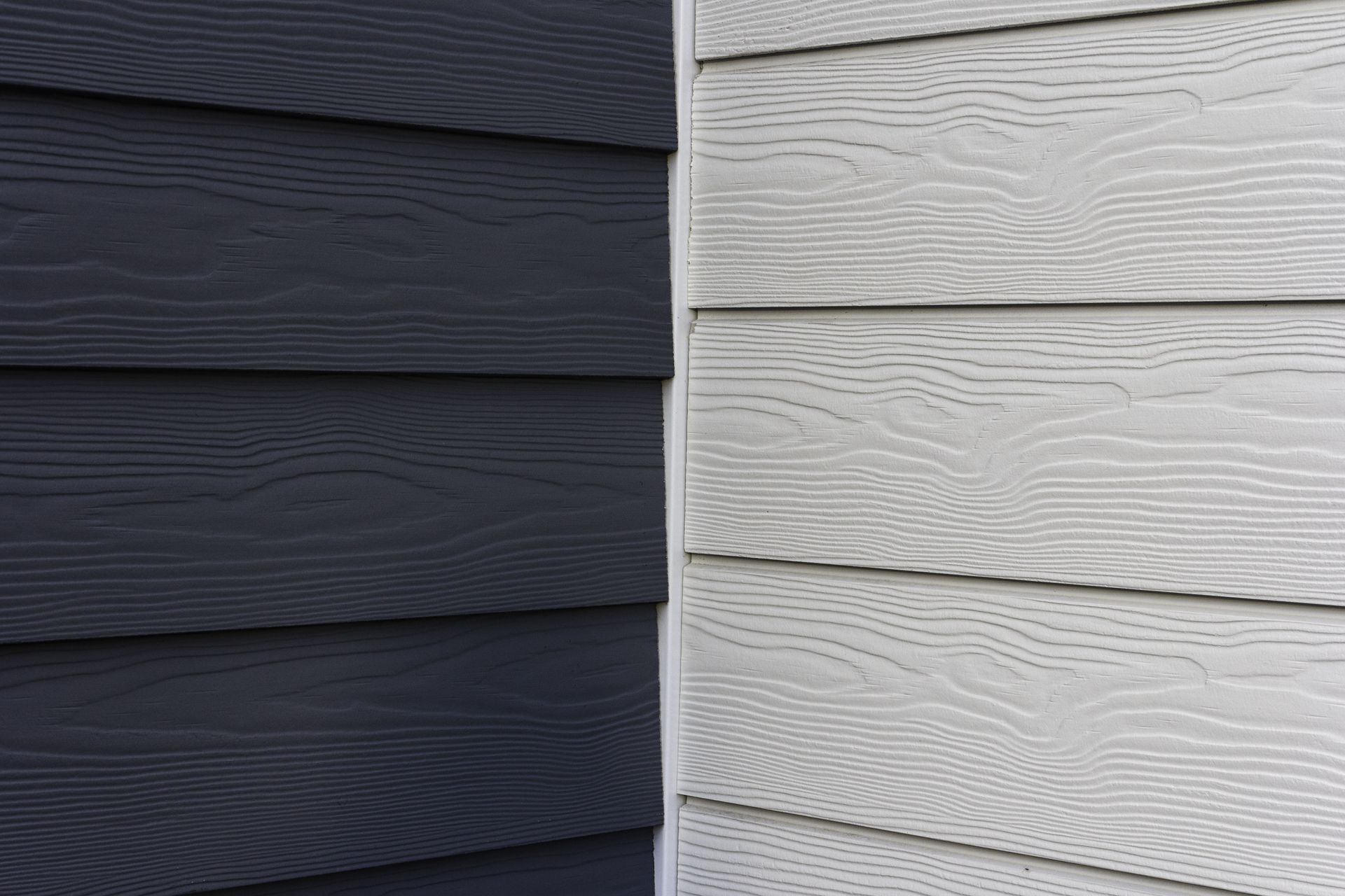 Dark gray and light gray wood siding meet at a corner.