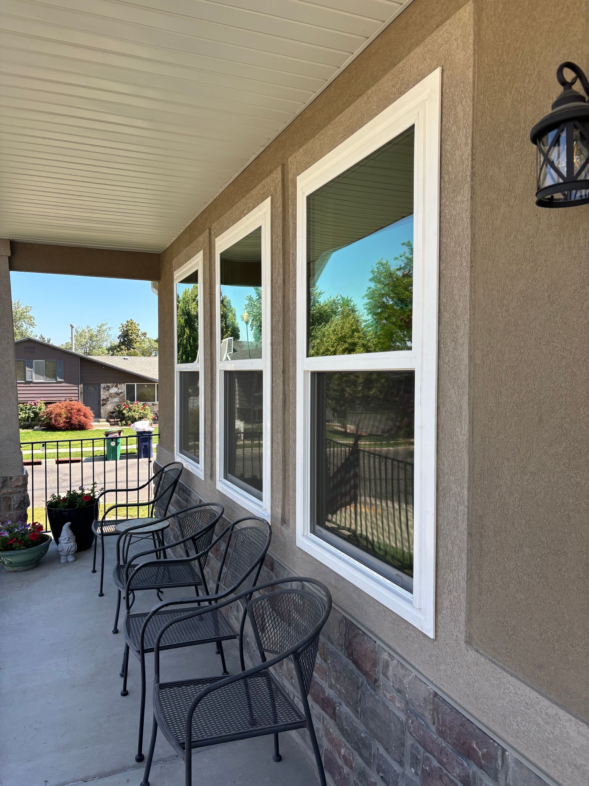 Porch with four tall windows, metal chairs, and a stone and stucco exterior.