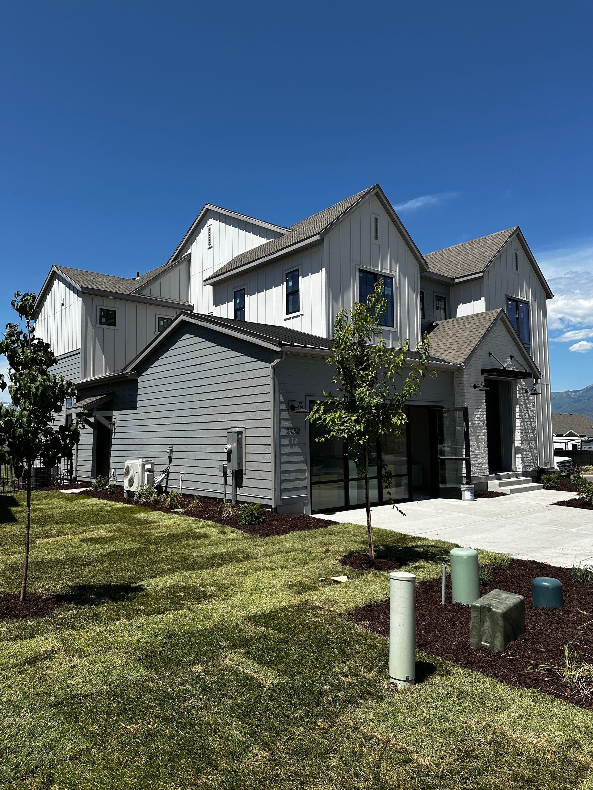 Modern multi-story house with gray and white siding under a blue sky.