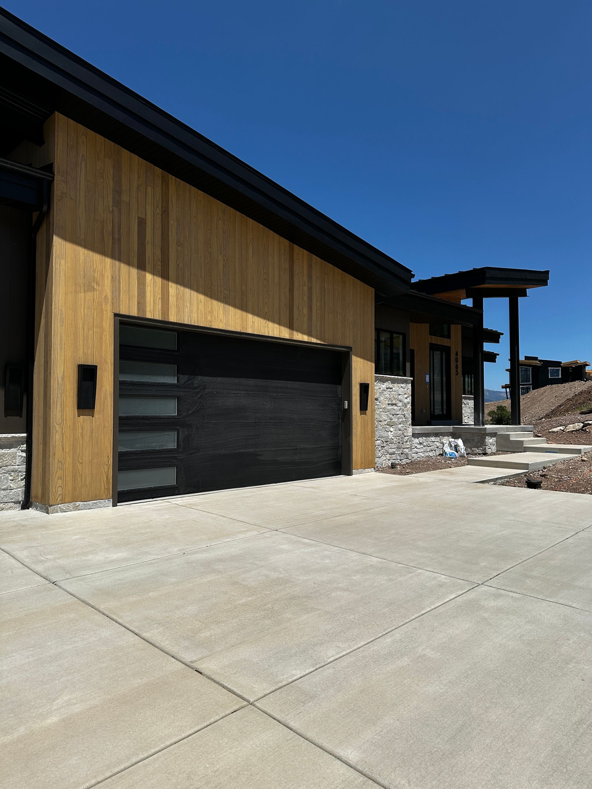 Modern house exterior with a dark garage door, wood siding, and stone accents.