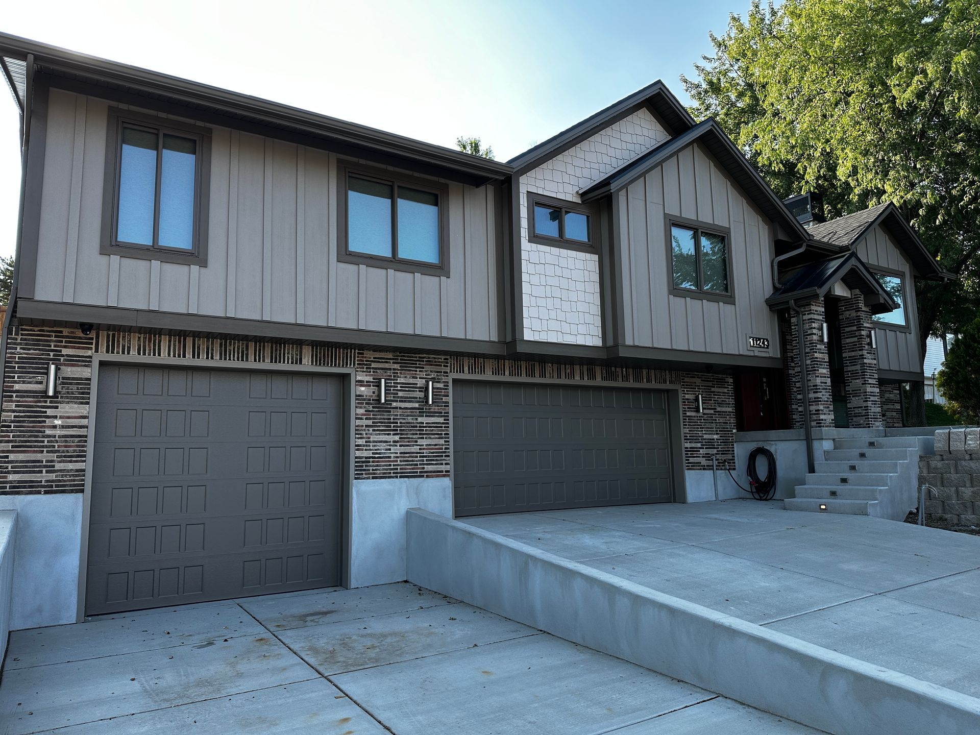 Two-story house with brown siding, stone accents, and a concrete driveway.