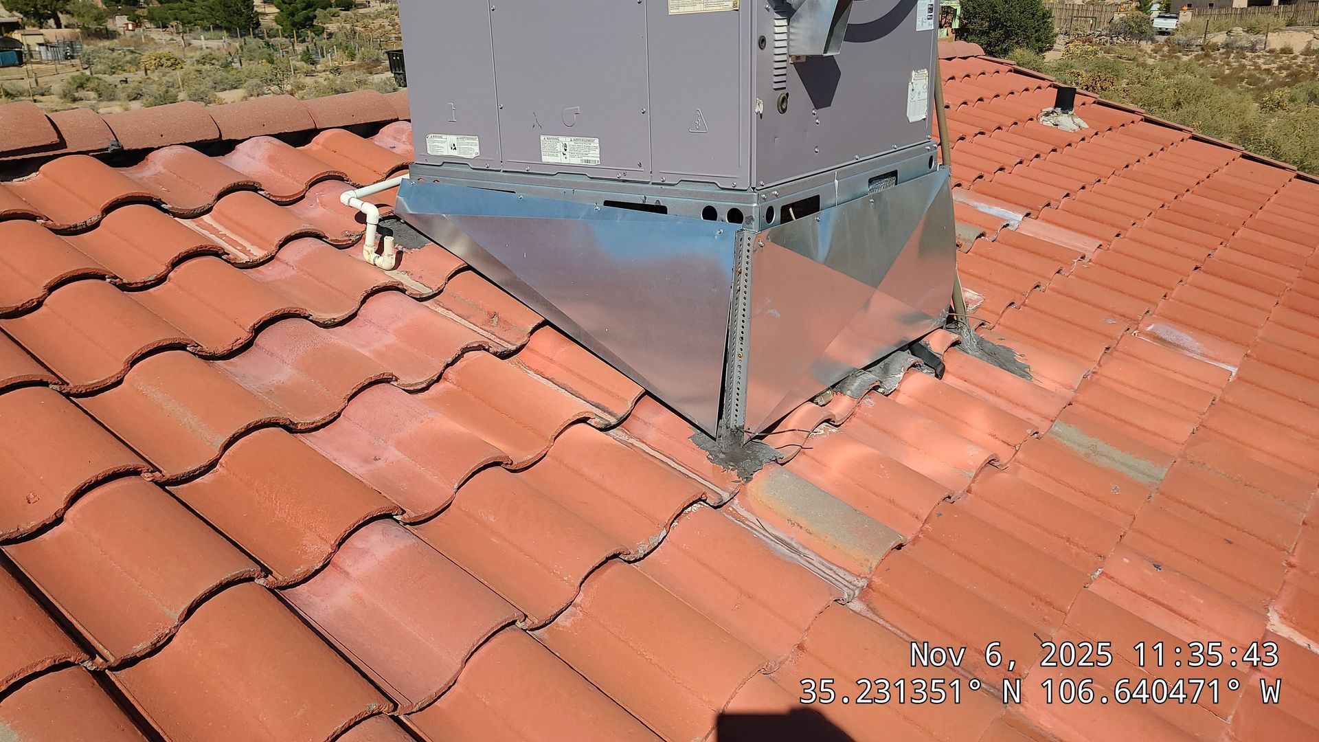 HVAC unit on red tile roof with metal flashing.
