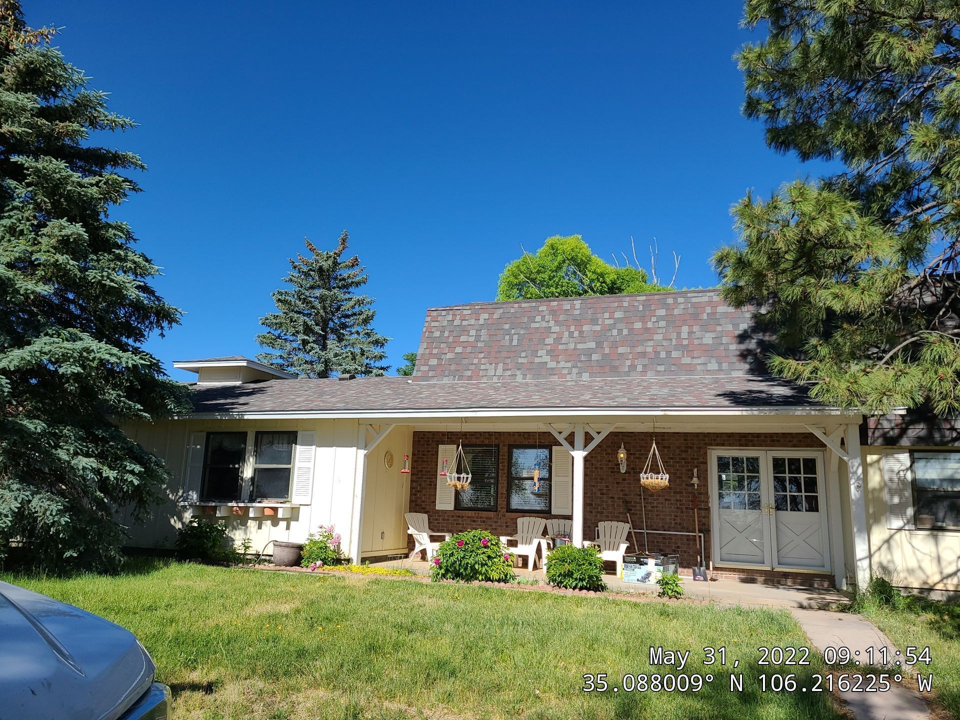 A one-story house with a porch and brown roof under a clear blue sky.