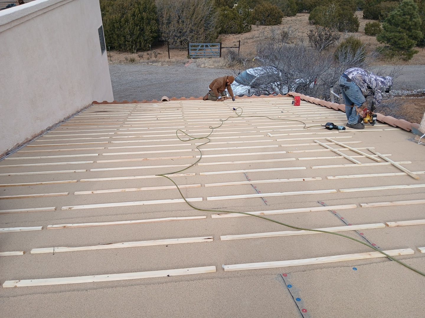Man cutting wood on a deck, dog nearby, in an outdoor setting.