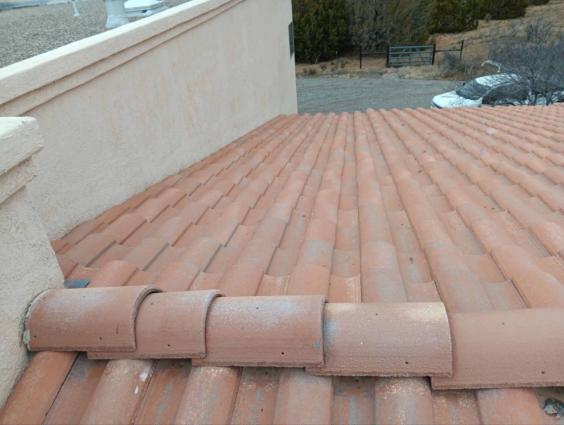 Clay tile roof with curved edge tiles, near a stucco wall.