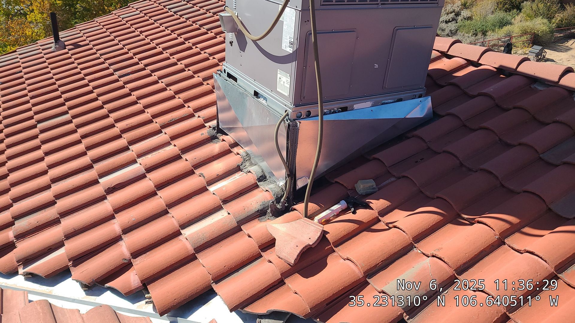 Chimney with a metal flashing on a red tile roof.