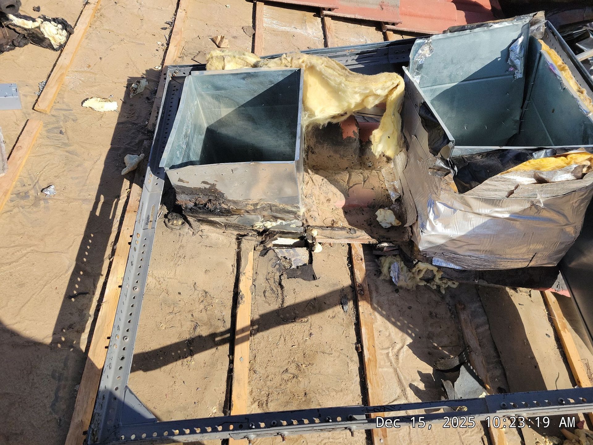 Ventilation system components on a roof, exposed insulation, metal ducting, and wood frame.