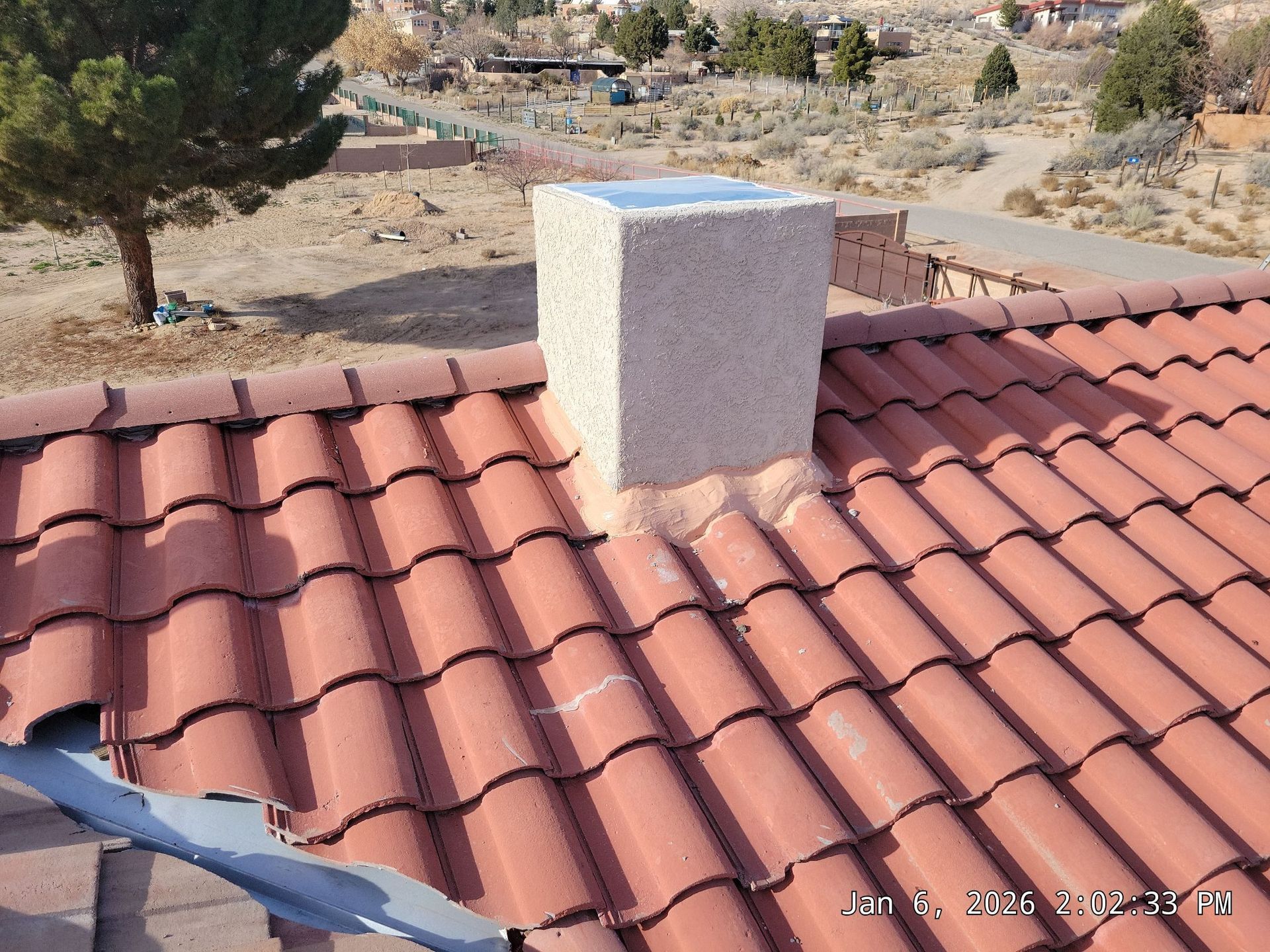 Red tile roof with a square, light-colored chimney. Sunny outdoor setting.