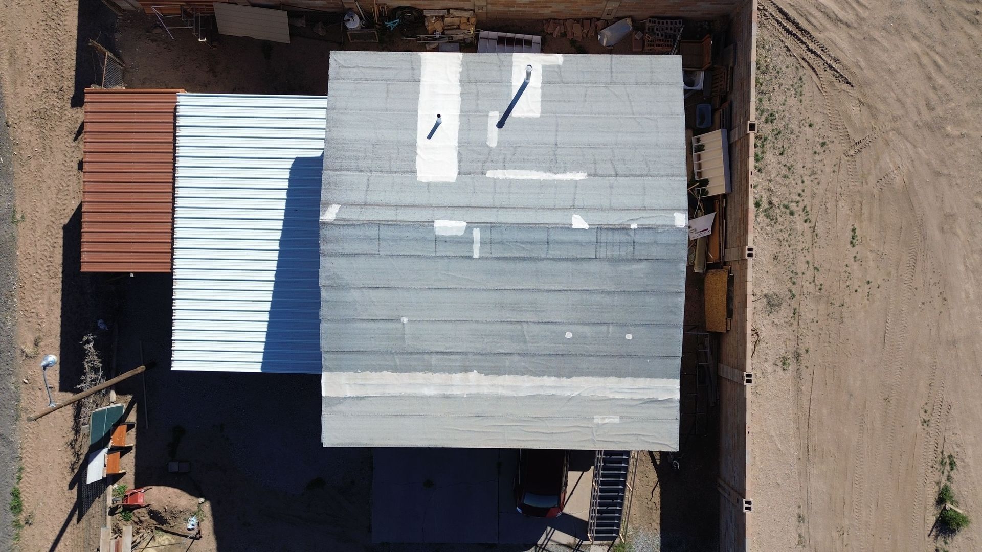 Overhead view of two attached buildings with corrugated metal roofs.