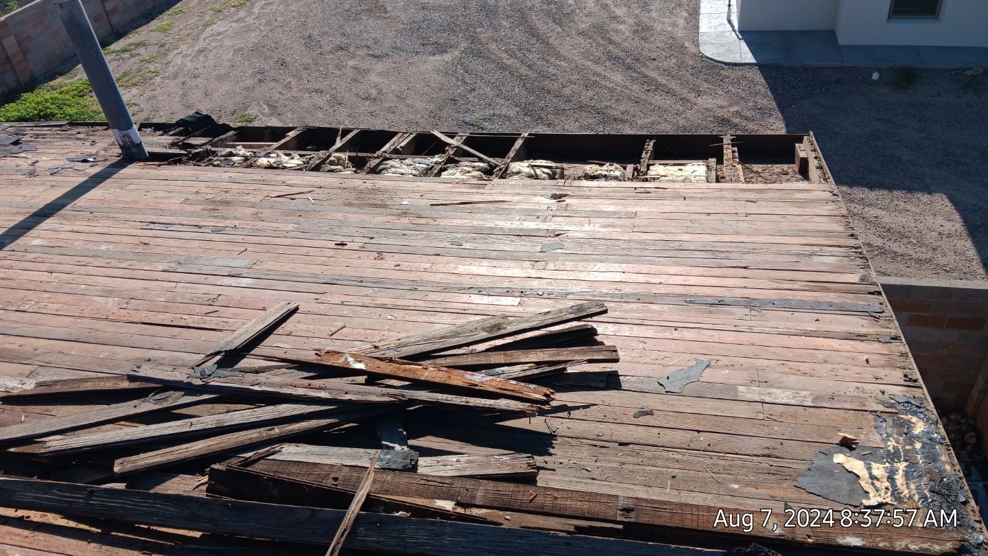 Rotted wooden deck with exposed joists, debris scattered, and a gravel yard visible.