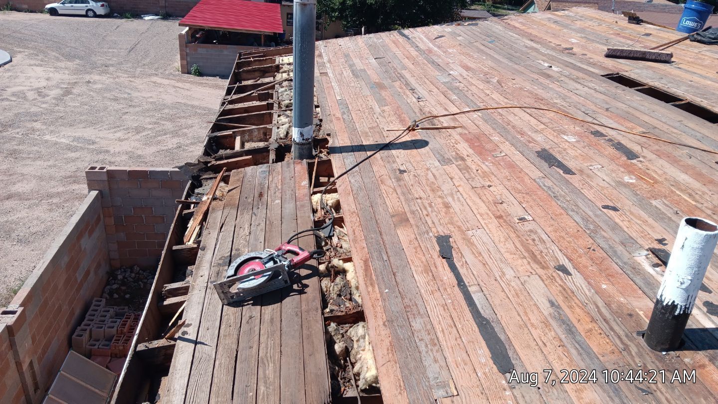 Roof construction: Wooden boards exposed, with a circular saw and metal pipes visible.
