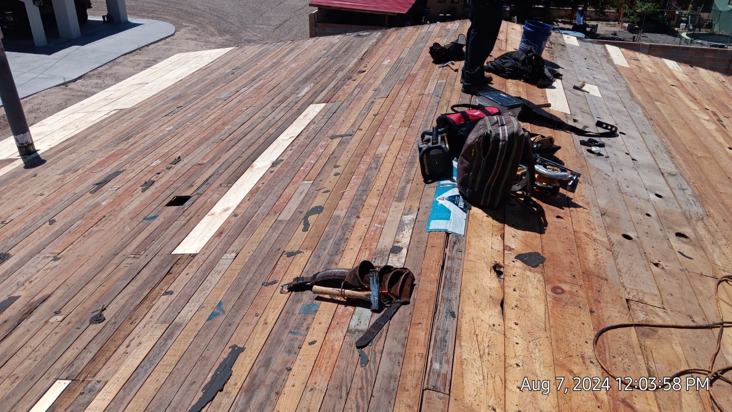 Wooden rooftop with scattered tools and a person standing, sunny day.