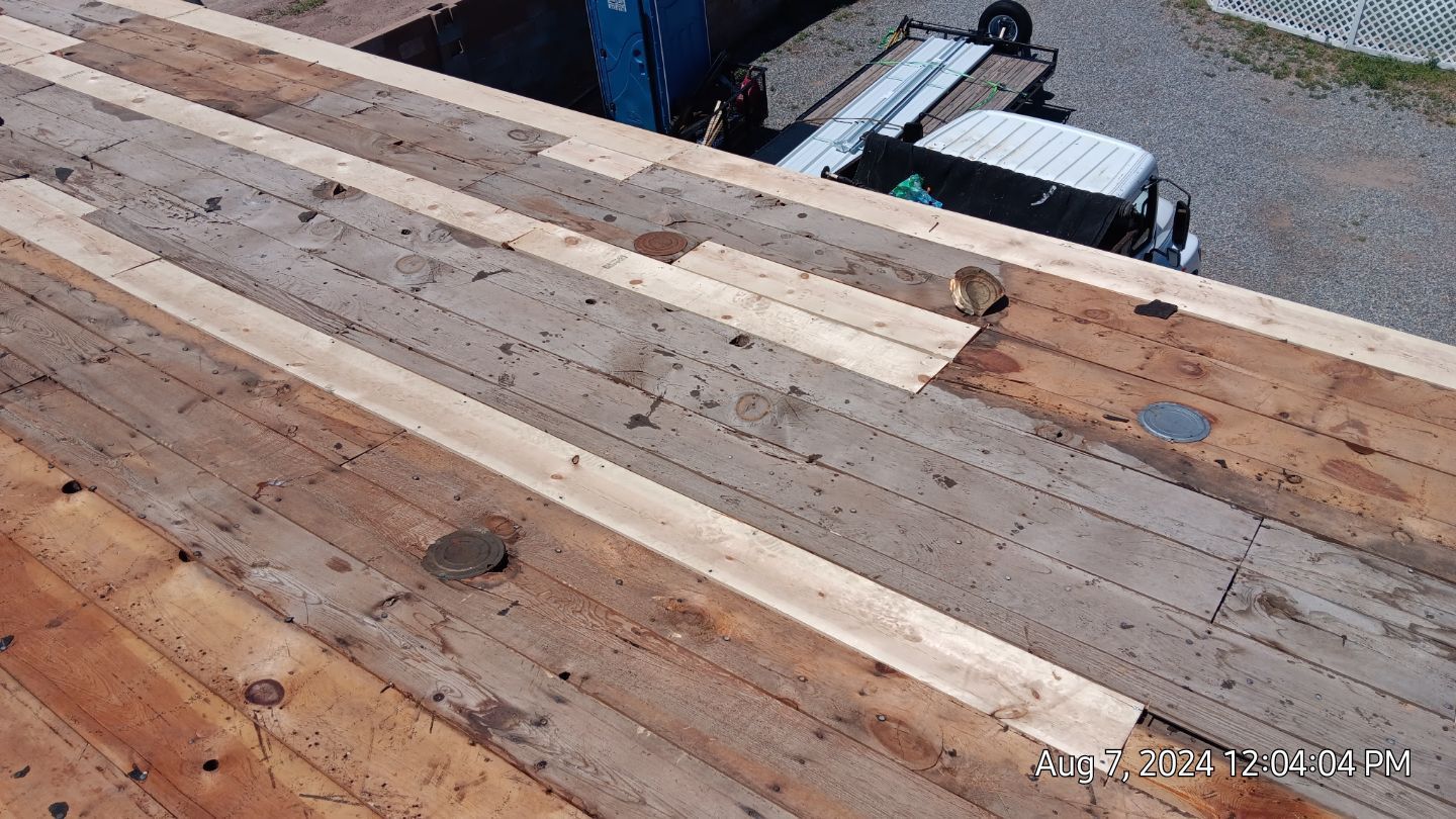 Overhead view of a wooden rooftop with new wooden planks being installed. 