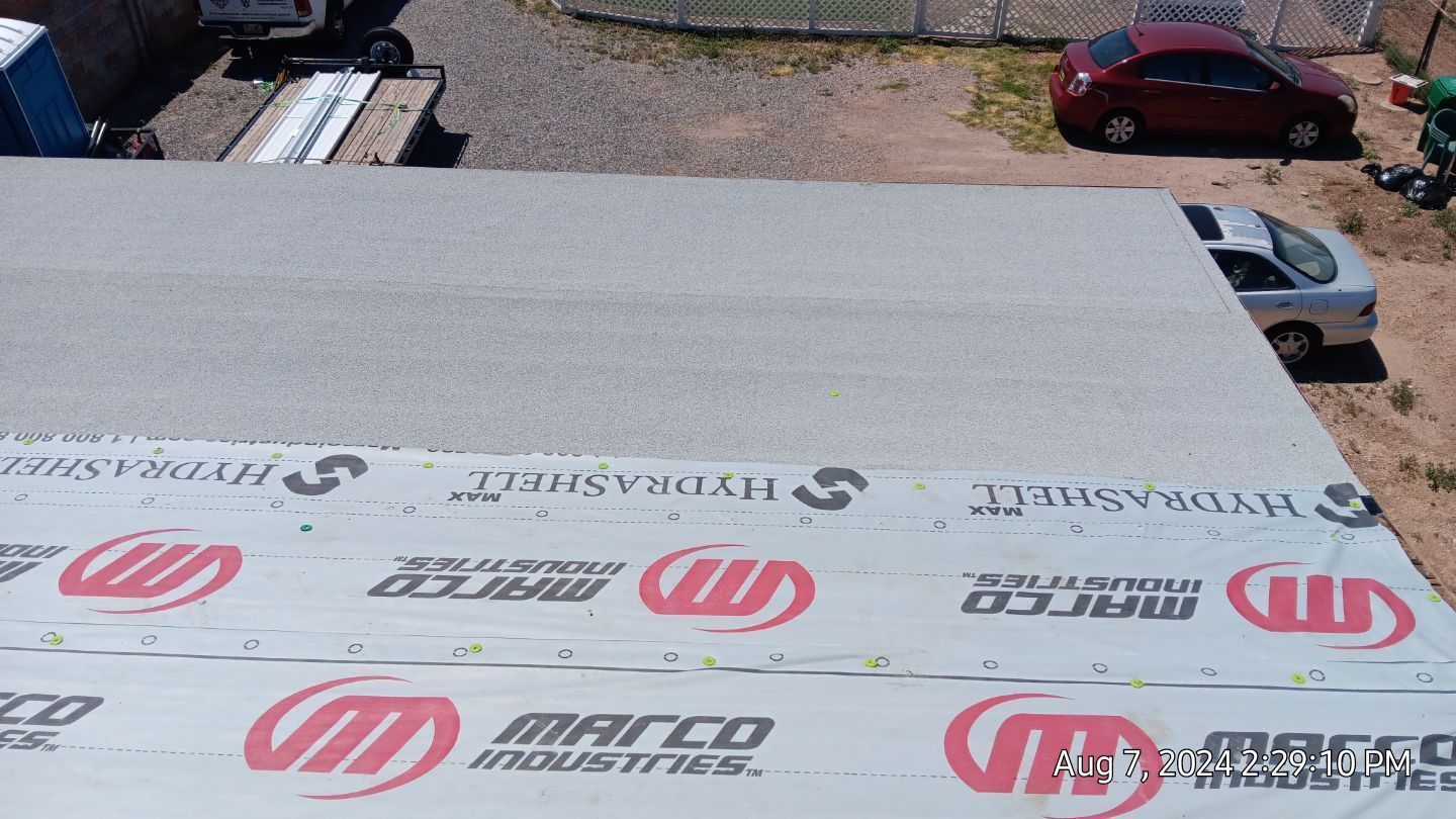 Flat roof with shingles and a car parked beside it.