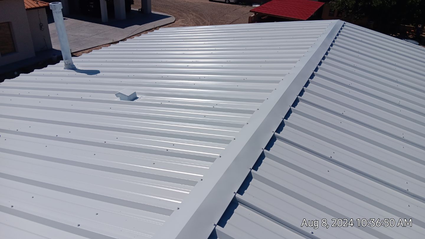 White metal roof with parallel ridges, viewed from above.