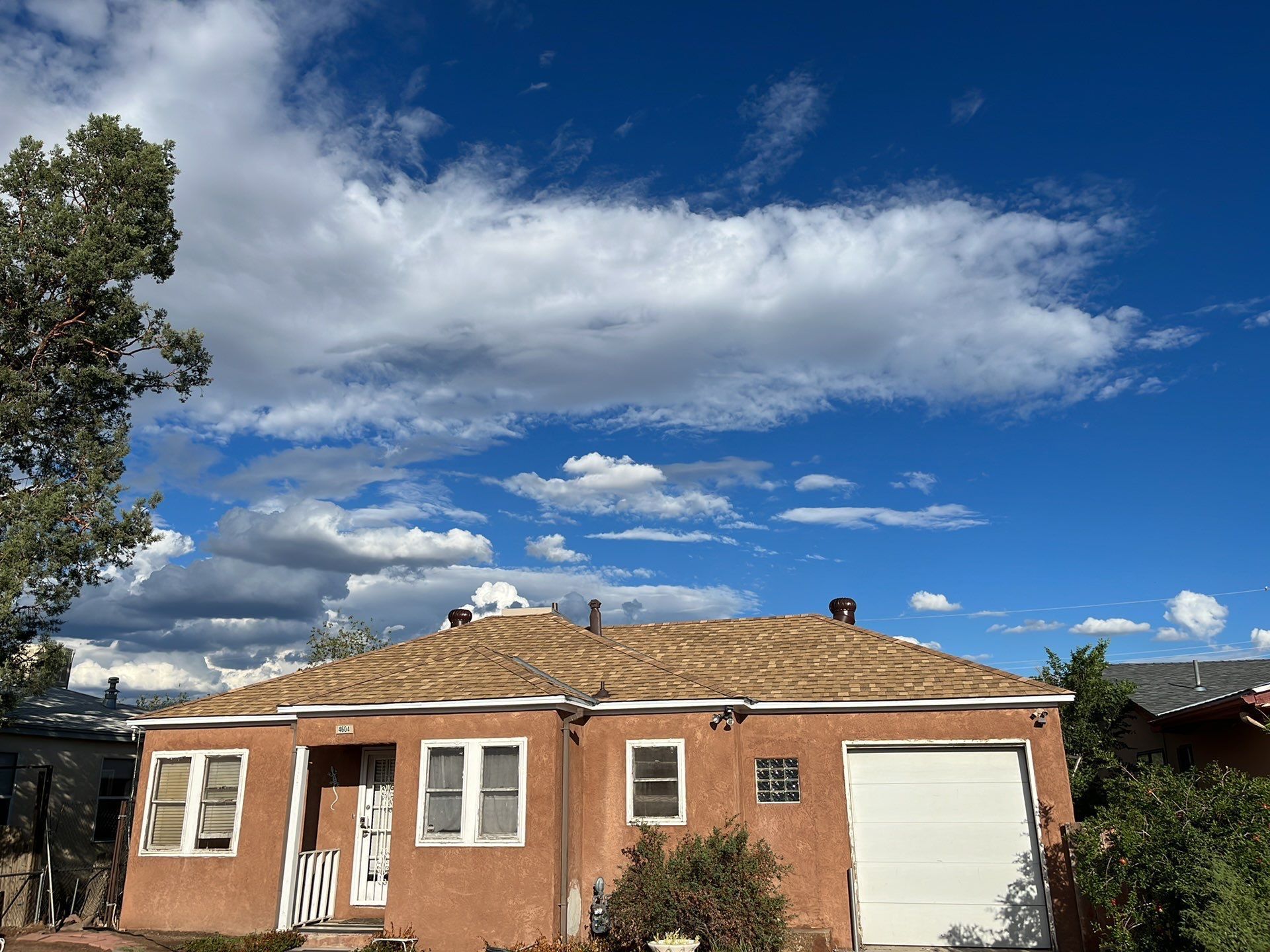 Orange stucco house under a bright blue sky with scattered clouds.