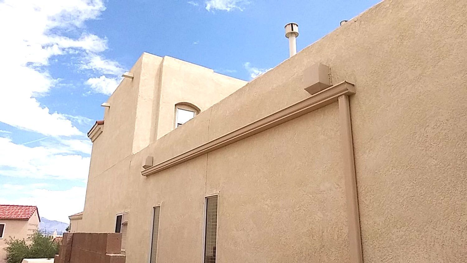Tan stucco building exterior under a partly cloudy blue sky.