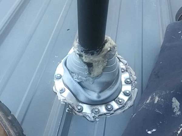 Vent pipe flashing on a metal roof, with sealant and screws.