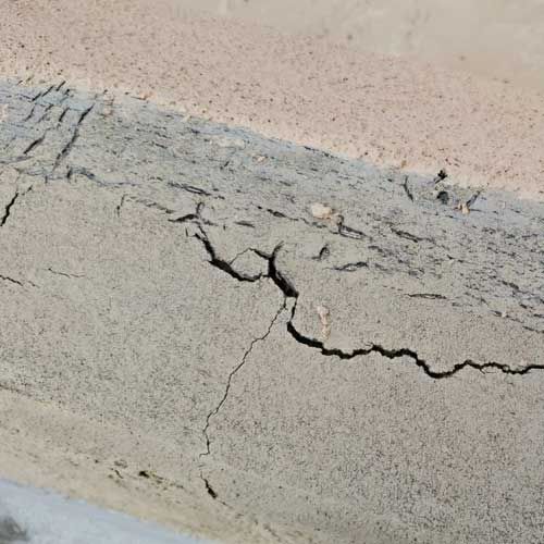 Close-up of cracked, gray and beige concrete surface.