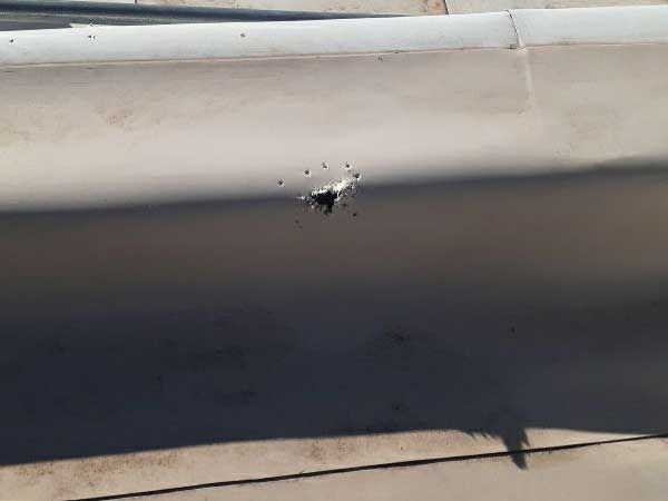 Hole in light-colored wall with shadow, likely from an impact.