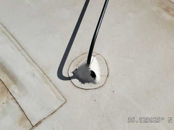 Black wire protruding from a white, sealed roof. Shadow present.