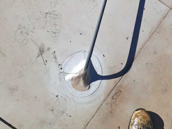 A gray metal chair leg in a circular indentation on a light-colored concrete surface.