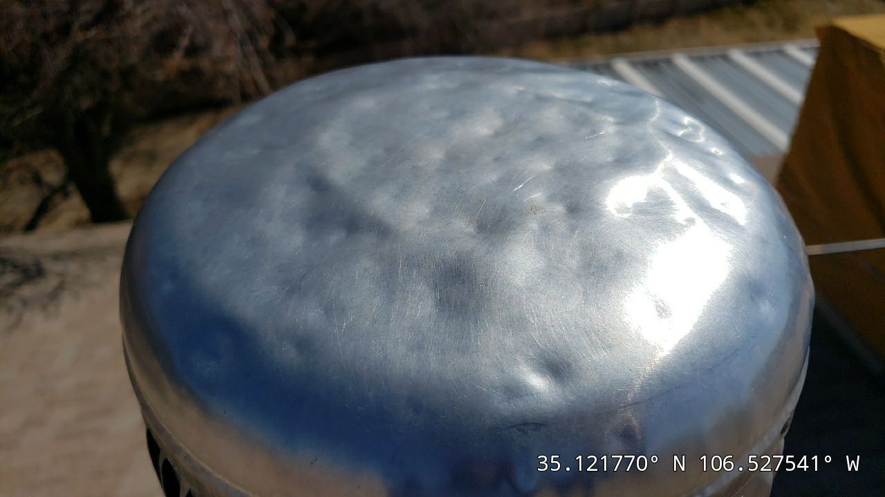 Silver-painted, domed object outdoors, showing multiple surface imperfections. Coordinates at bottom.