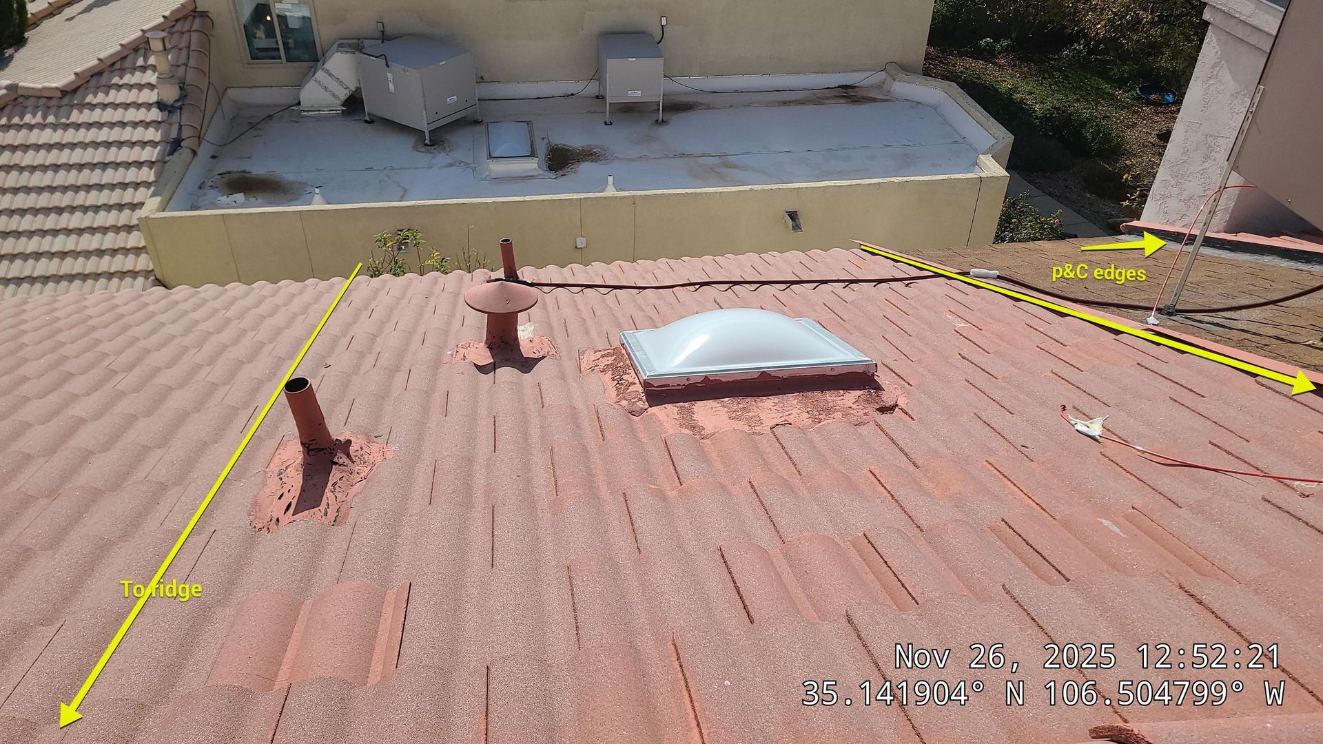 Red tiled roof with a skylight, vents, and yellow lines, likely electrical, on a sunny day.