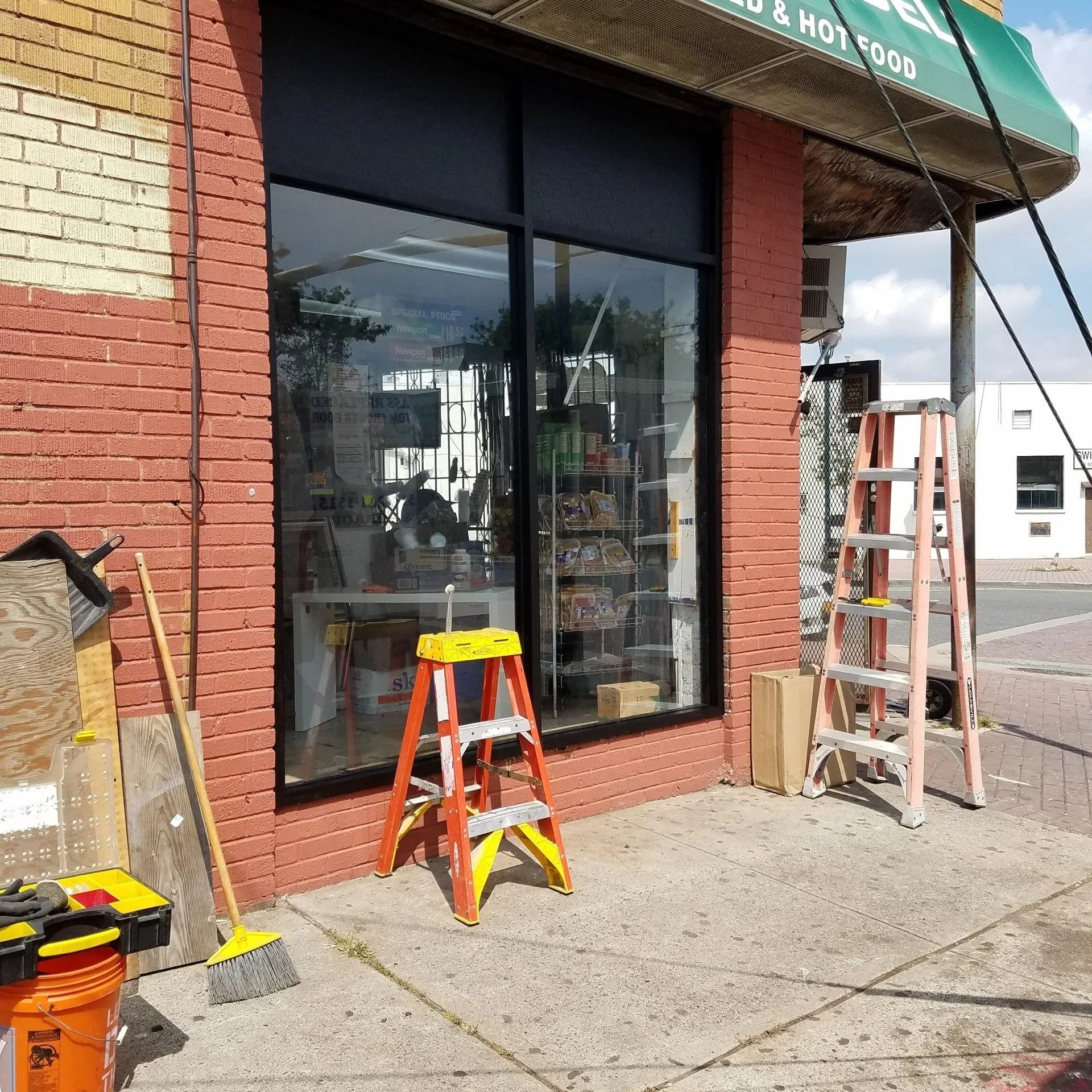 A store front with a green awning that says hot dogs