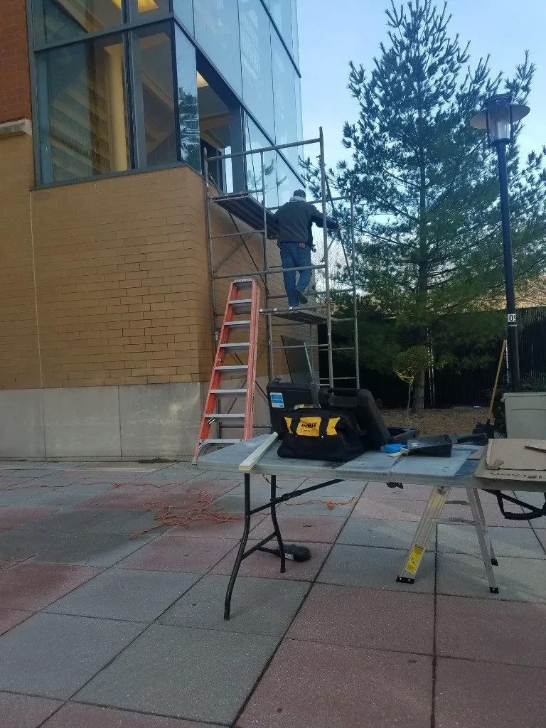 A man is standing on a ladder in front of a building