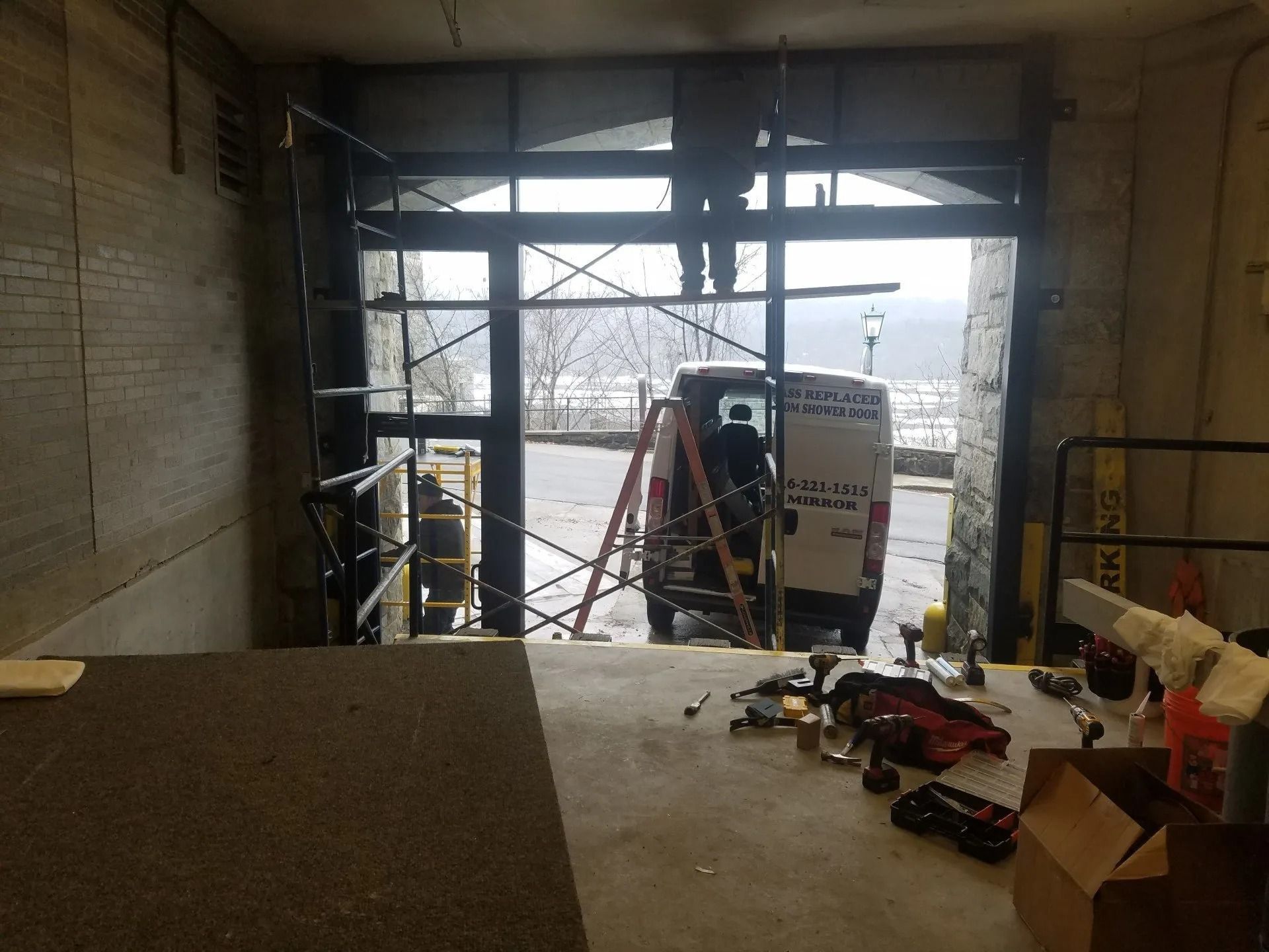 A white van is parked in a garage with a ladder.