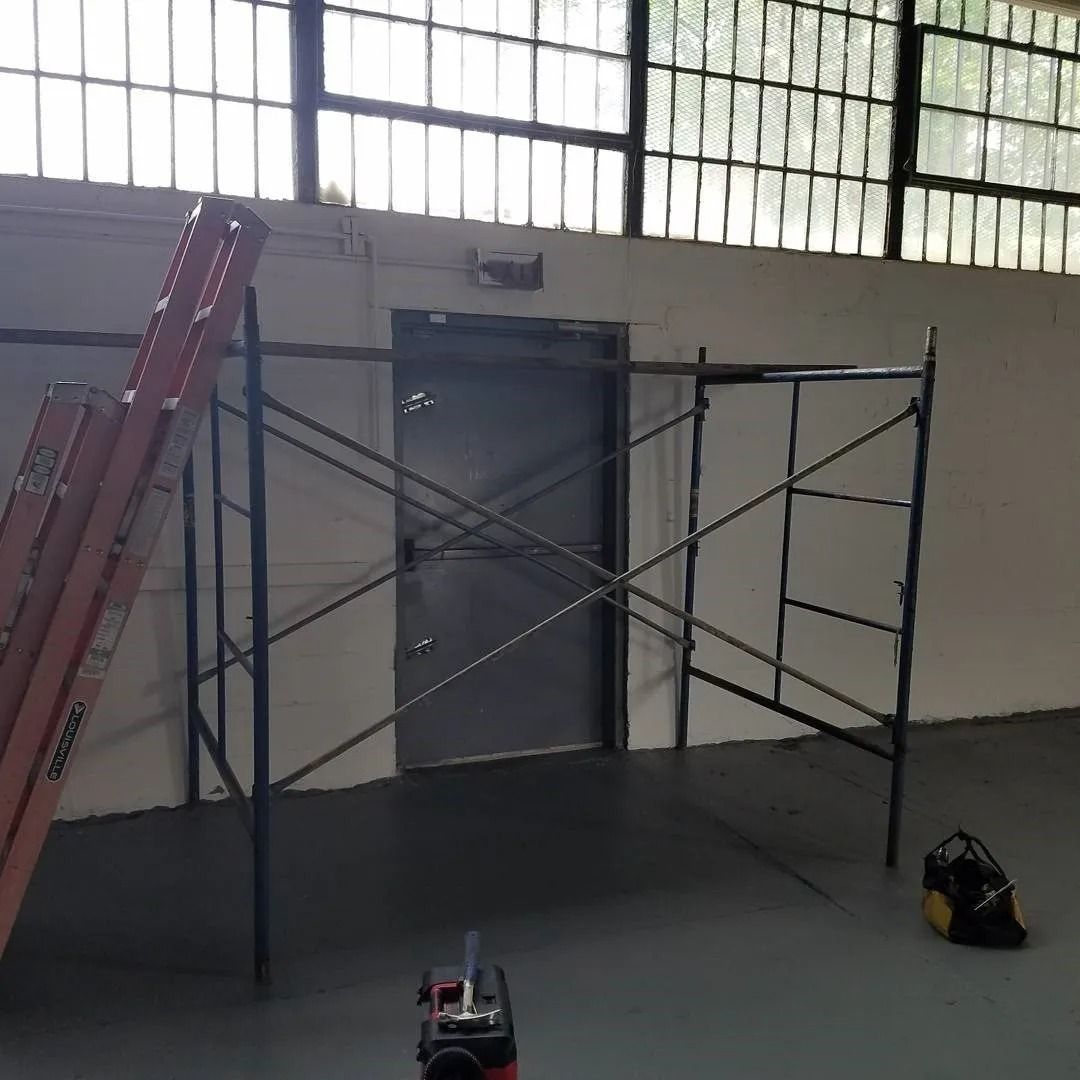 An empty room with a ladder and scaffolding in front of a door