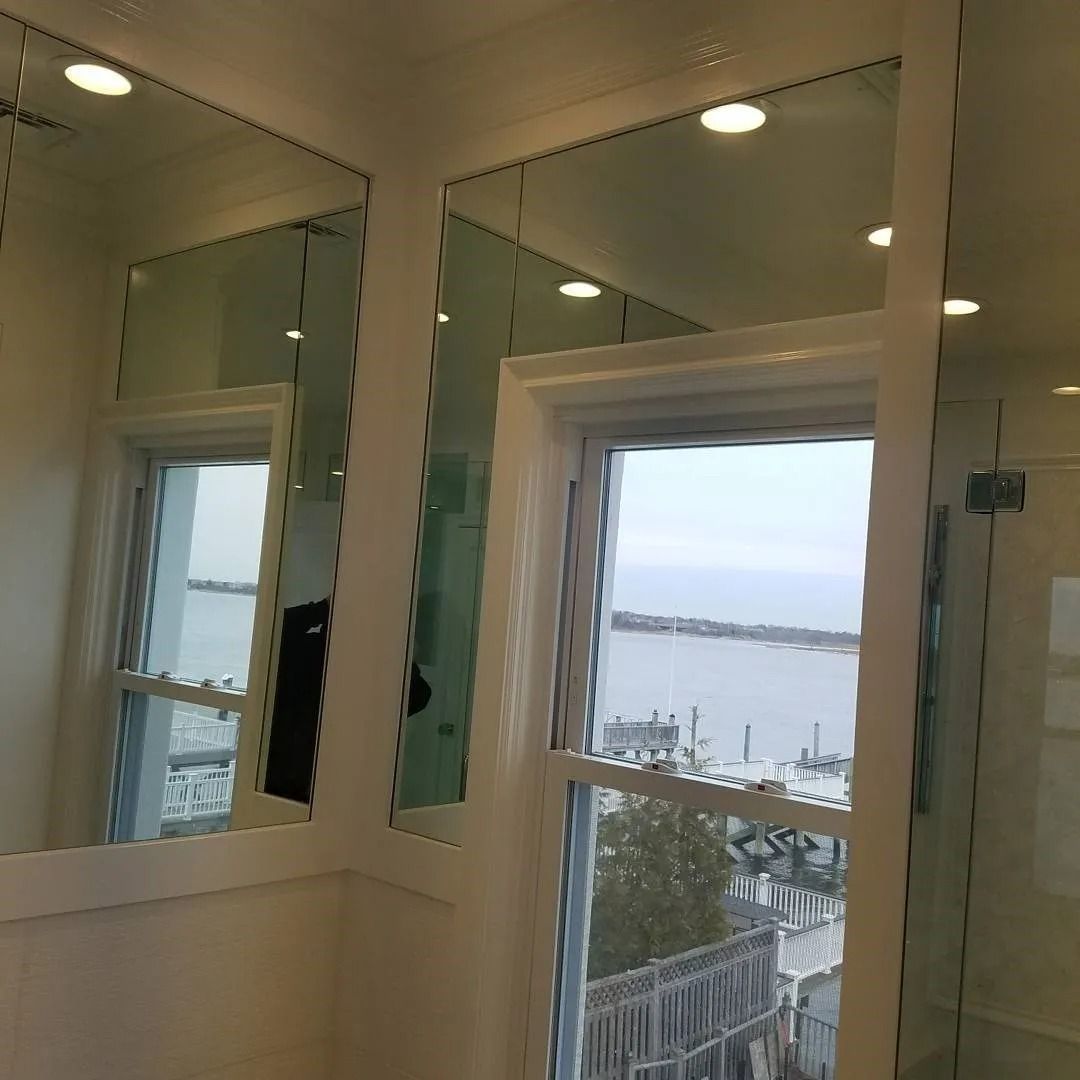 A bathroom with two mirrors and a window with a view of the ocean