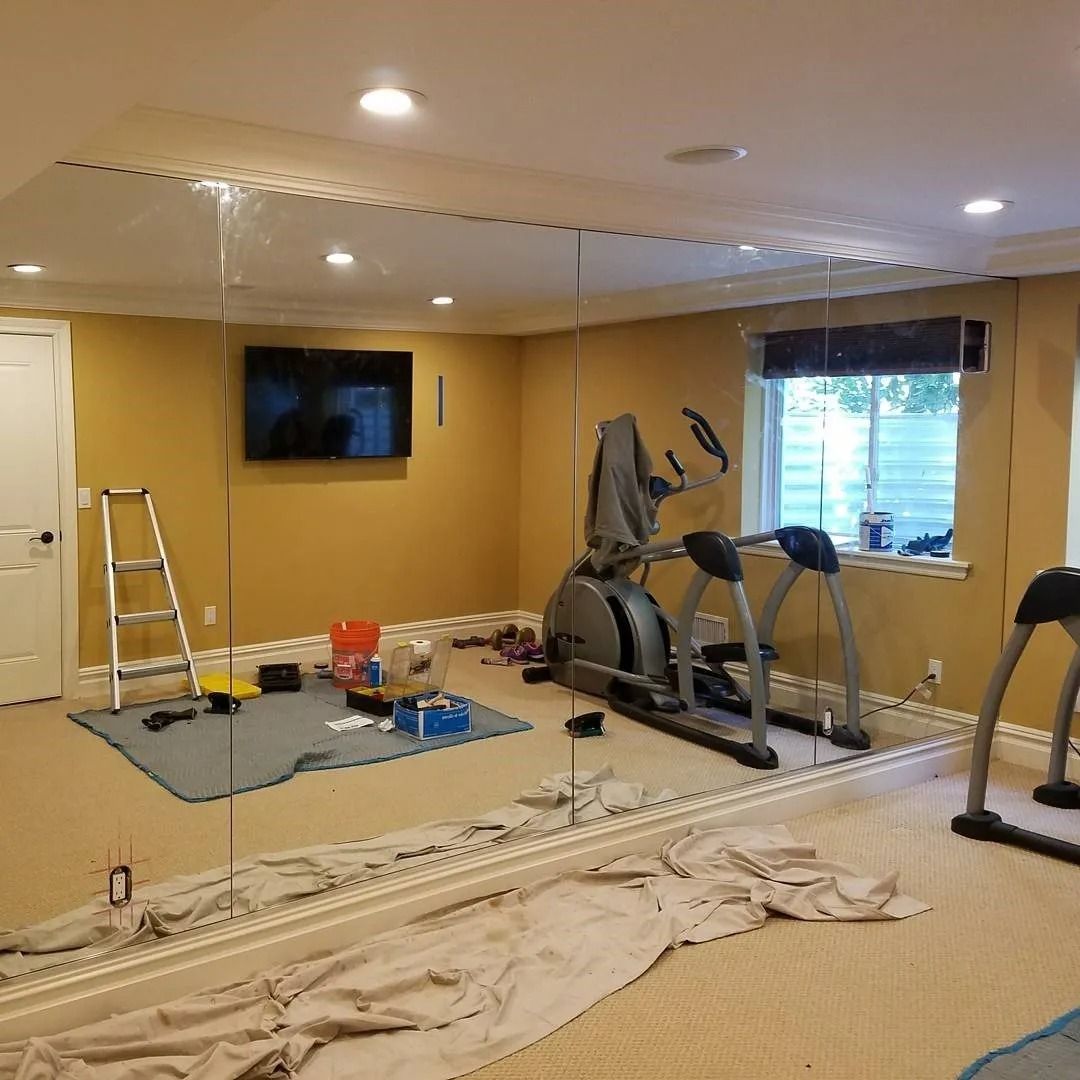 A gym with a large mirror on the wall and a treadmill.