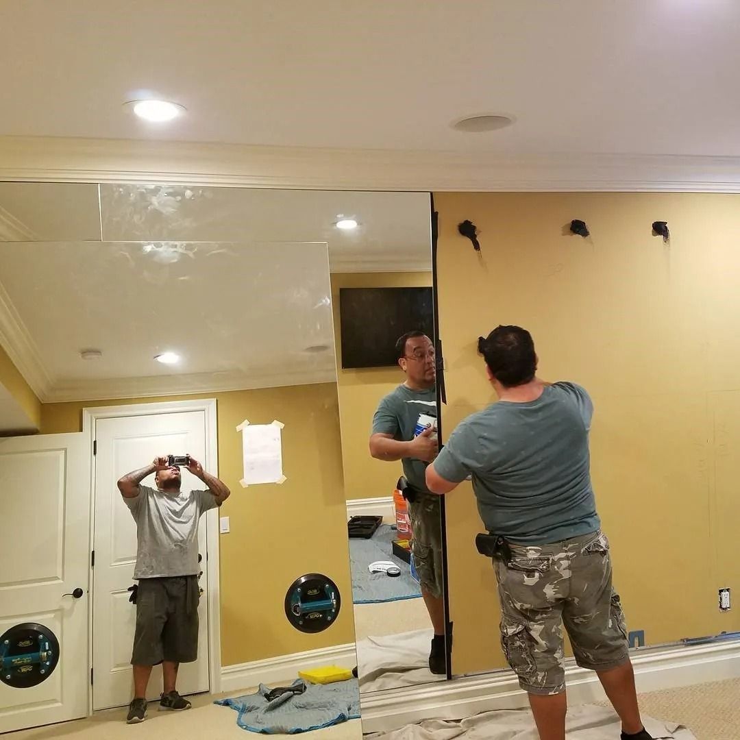 A man is standing in front of a large mirror in a room