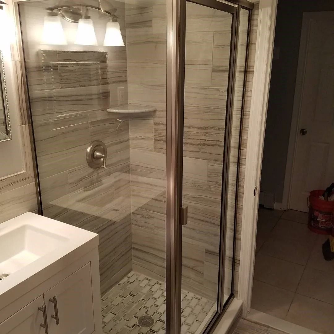 A bathroom with a walk in shower , sink and mirror.