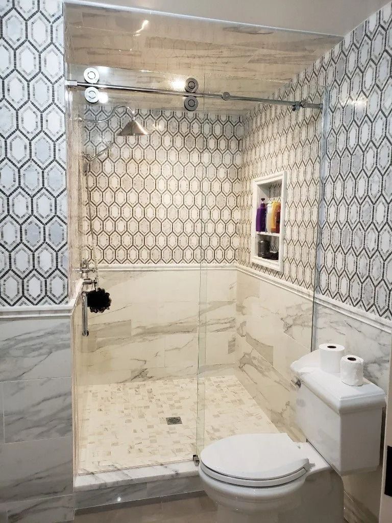 A bathroom with a toilet , shower , and sliding glass door.