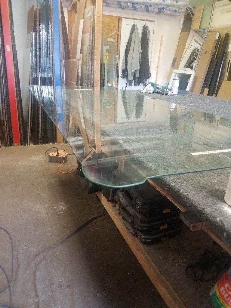 A glass table is sitting on top of a wooden table in a room.