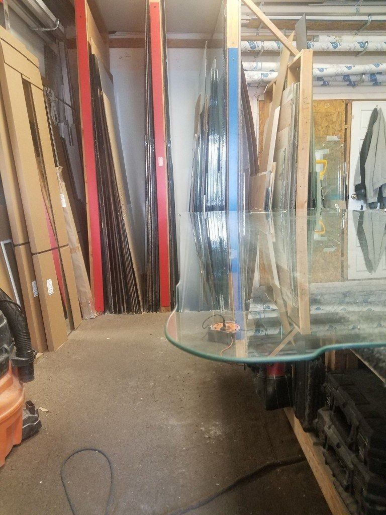 A glass table is sitting in a room filled with lots of boxes.