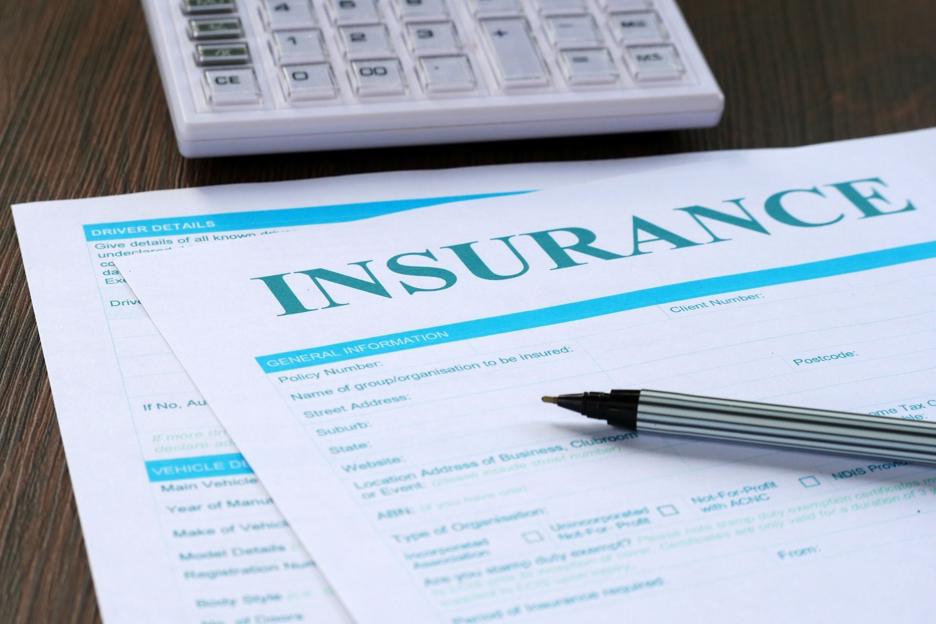 Insurance form with pen on desk beside calculator