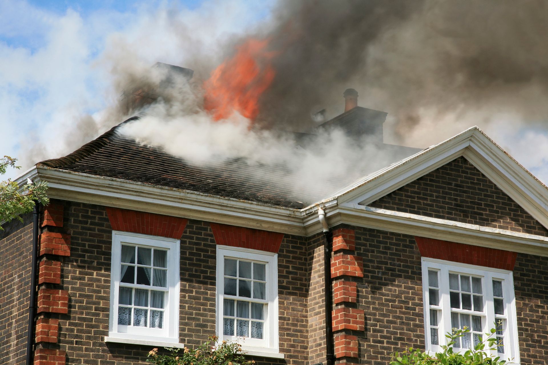 Smoke and flames rising from a house roof during a fire