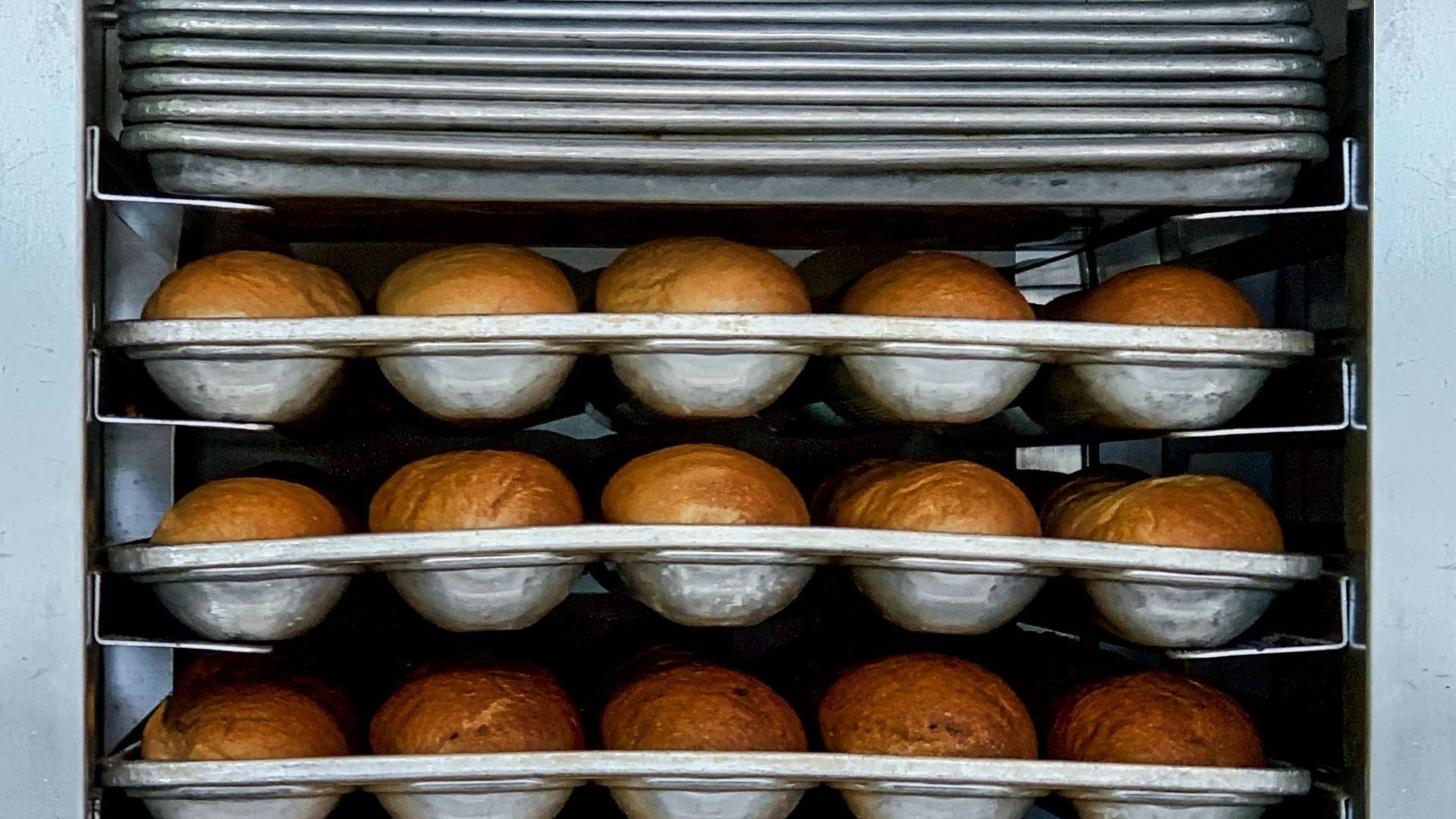Rows of bread cooking in a commercial oven.