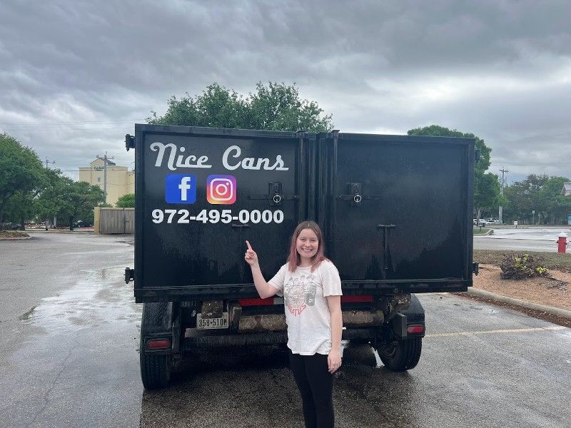 A woman is standing in front of a dumpster that says nice cans.