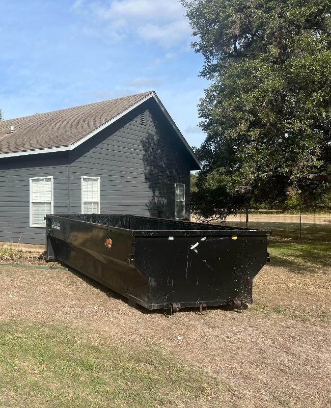 A dumpster is parked in front of a house.